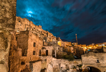 One of the many outer walls and hillsides of homes in the ancient prehistoric city of Matera Italy at night.