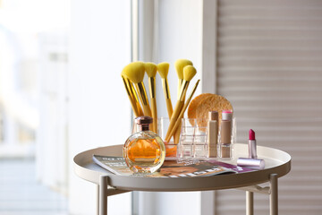 Different cosmetic products and makeup brushes on table