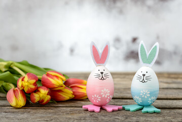 Cute Easter bunnies and a tulips on wooden background