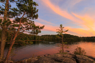 Brilliant sunset over northern Minnesota fishing lake fills sky with colorful clouds and subtle...