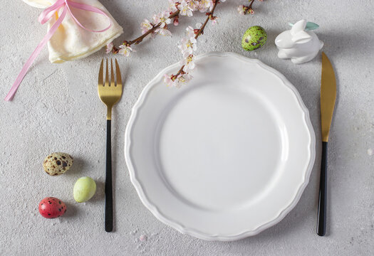 Easter table setting with quail eggs and bunny on light grey table. Elegance dinner. Top view