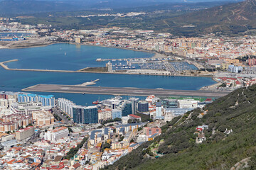 Fototapeta na wymiar Panoramic view over Gibraltar harbour from the top of the Rock of Gibraltar. The airport runway juts out into the water.