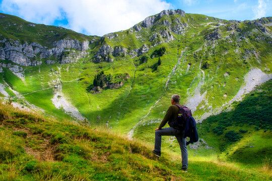 Hiker in Swiss Alps looking at mountain view, Biel Kinzig, Uri, Switzerland