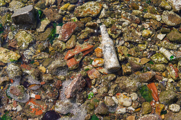 Broken glass bottle and garbage from the sea on the beach
