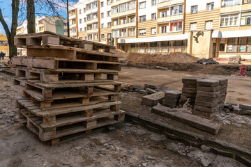 Old worn-out wooden pallets at a construction site in the city. Repair of the city street and sidewalk.