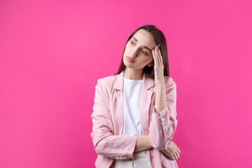 Portrait of beautiful young woman in pink jacket thinking isolated on red background