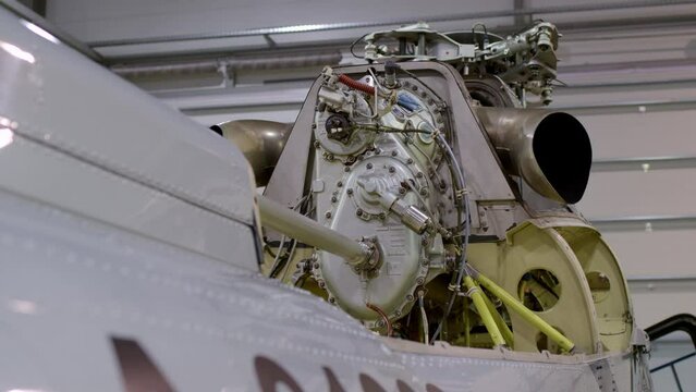 close up view of engine of gray helicopter. dismantled aircraft is in hangar for maintenance or inspection and permission to fly.