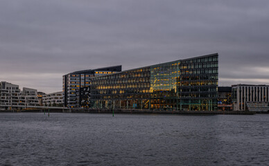 Aller Media AS headquarters, futuristic dark building on Havneholmen in Copenhagen at sunset, Denmark on November 2021. Designed by PLH Architects. Overcast day and almost monochrome image.