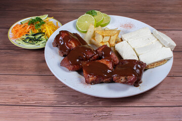 Traditional Colombian food, grilled ribs with bbq sauce, chocolo arepa with cheese, salad, french fries and salad
