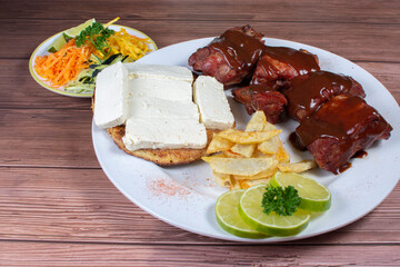 Traditional Colombian food, grilled ribs with bbq sauce, chocolo arepa with cheese, salad, french fries and salad