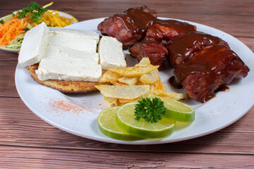 Traditional Colombian food, grilled ribs with bbq sauce, chocolo arepa with cheese, salad, french fries and salad
