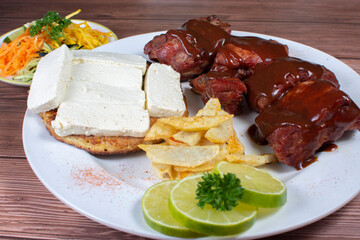 Traditional Colombian food, grilled ribs with bbq sauce, chocolo arepa with cheese, salad, french fries and salad