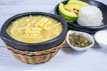 Ajiaco, traditional Colombian food, accompanied by rice, milk cream, avocado, capers and salad