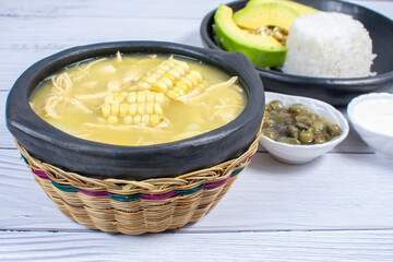 Ajiaco, traditional Colombian food, accompanied by rice, milk cream, avocado, capers and salad