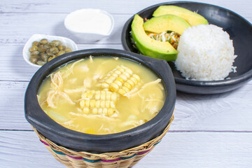 Ajiaco, traditional Colombian food, accompanied by rice, milk cream, avocado, capers and salad