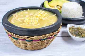 Ajiaco, traditional Colombian food, accompanied by rice, milk cream, avocado, capers and salad