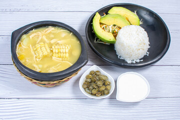 Ajiaco, traditional Colombian food, accompanied by rice, milk cream, avocado, capers and salad