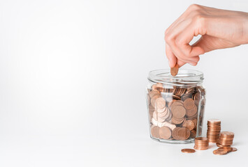 Fototapeta na wymiar Human hand putting coins in glass jar. Money saving concept.