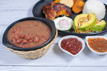 Traditional Colombian lunch, accompanied by chicken, beans, fried egg, arepa, rice, avocado, ripe plantain and salad