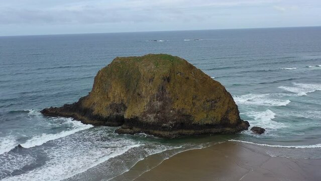 The Pacific Ocean gently washes against a massive sea stack along the Oregon's shoreline, not far west of Portland. The scenic U.S. Route 101 runs right along this beautiful part of the west coast.