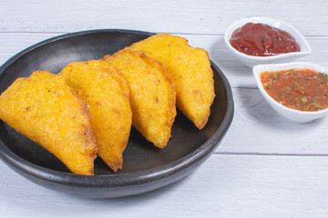 Traditional Colombian snack, chicken empanada with hogao, lemon and sauce