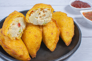 Traditional Colombian snack, chicken empanada with hogao, lemon and sauce