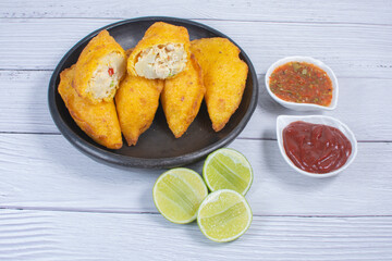 Traditional Colombian snack, chicken empanada with hogao, lemon and sauce