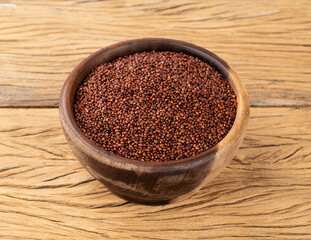Raw red quinoa in a bowl over wooden table