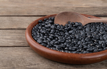 Black beans in a plate over wooden table. Short depth of field