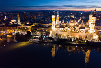 Fototapeta na wymiar Scenic twilight view from drone of illuminated Basilica of Our Lady of Pillar on bank of Ebro river in Spanish city of Zaragoza ..