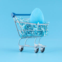 Blue Easter egg in shopping cart for Easter shopping concept.