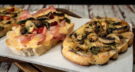 Large bruschettas with cheese, mushrooms, prosciutto and tomato in different combinations. Mediterranean food concept.High view