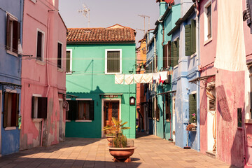 Pastel green, pink and blue houses in Burano, Venice, Venezia, Italy, picturesque town square, laundry hanging in the street