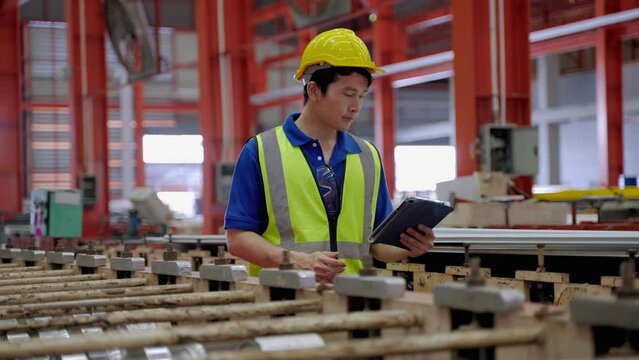 Supervisors or employees within the factory are walking to check the work of the machines within the factory, checking and checklist of machines to be in a ready-to-use condition
