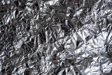 Abstract crumpled silver foil background. Shiny rumpled foil sheet texture.