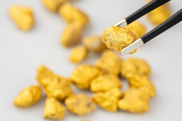 Goldsmith is using a tool to pick gold nuggets from the mine on a white background to inspect.