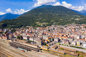 Fototapeta na wymiar Summer view from drone of Domodossola city with railway station at foot of Italian Alps