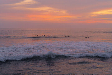 Surfers catch waves at sunset in the ocean. Surfing background