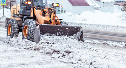 Big orange tractor cleans up snow from the road and loads it into the truck. Cleaning and cleaning...