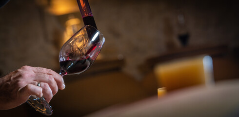 FRANCE, GIRONDE, SAINT-EMILION, SAMPLING A GLASS OF WINE IN A BARREL WITH A PIPETTE FOR TASTING AND VINIFICATION MONITORING