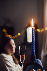 A candle and a glass on the table in the house. Pleasant evening, the girl rests. Vertical photo.