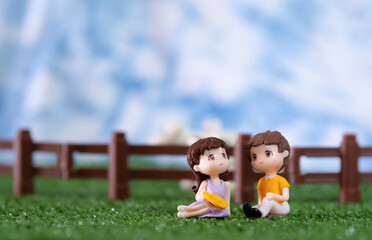 Cute Miniature dolls boy and girl sitting on the grass ground in the Farm with love and cute
