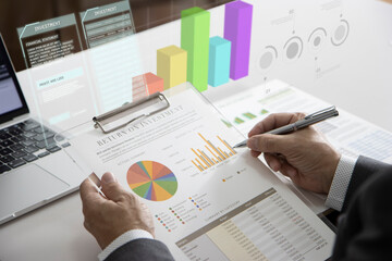 Businessman or analyst reviewing financial statement with augmented reality three-dimentional bar graph while analyzing a return on investment and business performance