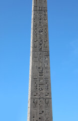 Egyptian obelisk with engraved hieroglyphs on blue sky background