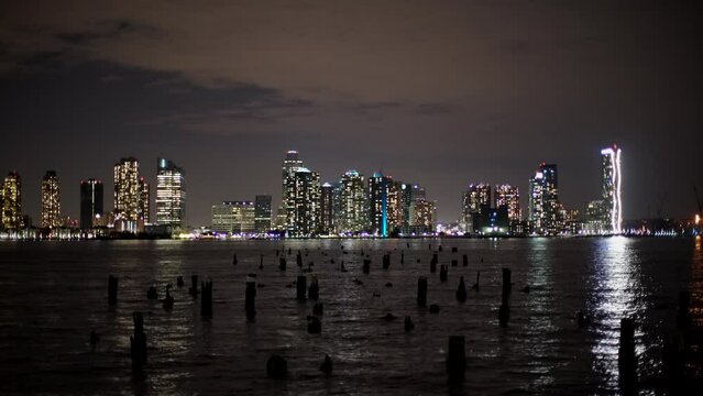 View of New Jersey from NYC at Night. Skyscrapers illuminated and Taxi Boat passing by