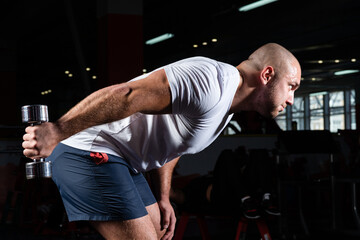 Male bodybuilder engaged with dumbbells in the gym