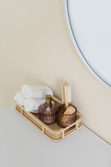 Fototapeta na wymiar Rolled towels and bath accessoires in wooden basket near mirror