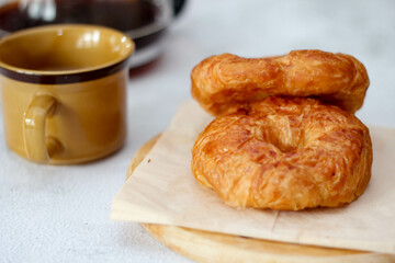 A croissant served with coffee is placed on a white table.