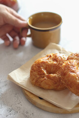 A croissant served with coffee is placed on a white table.