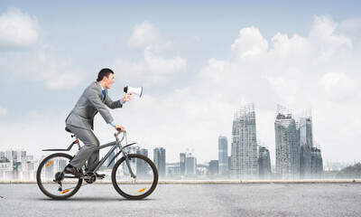 Businessman with megaphone in hand on bike